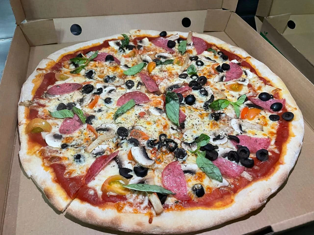 Pizza La Real con aceitunas, choclo y cebolla recién salida del horno